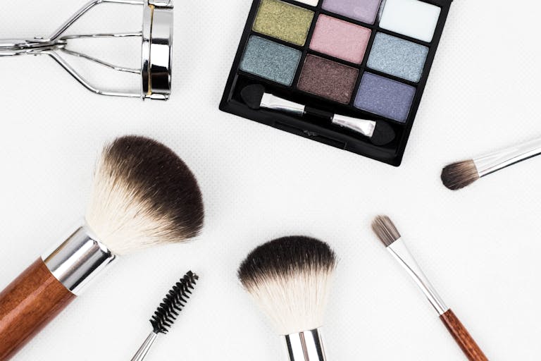 Top view of makeup tools and a colorful eyeshadow palette arranged artistically.